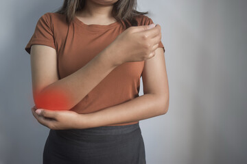 Young Asian woman holding her elbow in pain and discomfort.