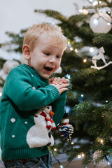 Little boy clapping hands in front of Christmas tree with amazed surprised emotion