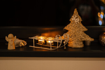 Wooden sled with candles handmade Christmas tree and angel in window at night