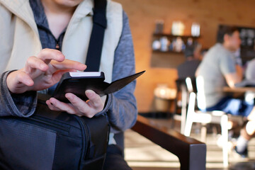 Close-up of a woman browsing drink menu on cell phone inside coffee shop