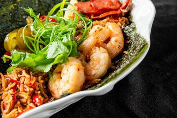 Close-up of a vibrant seafood rice bowl with shrimp, sausage, seaweed, jalapeños, cilantro, and vegetables, garnished with green onions
