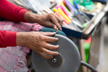 Sharpening knives blade on a whetstone, indian knife sharpener at work, wheel propelled via pedals, culture of India