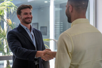 Fototapeta premium Two businessmen shaking hands in modern office, establishing a successful partnership