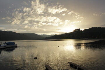 Beautiful sunset with golden sky reflected over lake and mountains.