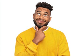 Young man in vibrant yellow sweater thoughtfully smiling with hand on chin displaying curiosity and playfulness showcasing introspection and creativity against a clean white backdrop