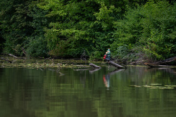 A water sprite figurine sitting on a log near the water’s edge.

