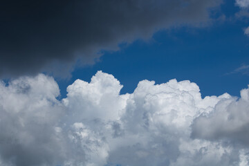 A dramatic sky with a dark storm cloud, a patch of blue sky, and white cumulus clouds. Hope in the midst of a storm