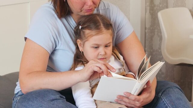 Small Caucasian child learns to read with help from a caregiver. Preschool development in a warm and supportive space. Close up.