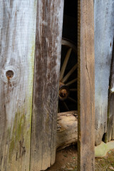 Photograph of an old wagon wheel seen through a gap in a weathered barn wall, Cades Cove, Great Smoky Mountains, Tennessee