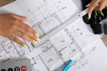 Hands Measuring Construction Blueprint with Various Tools and Equipment Effectively