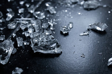 Close up of shattered glass pieces on dark surface showing textures and reflections