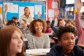 group of diverse middle school students in classroom, actively raising their hands to answer a teacher question. Smiling teacher whiteboard in background, colorful educational posters on walls