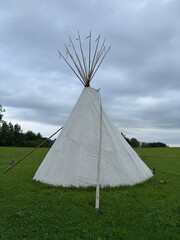 A traditional teepee is beautifully placed in a scenic field, surrounded by natures beauty