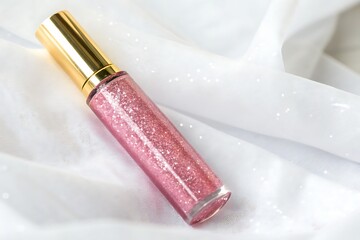 Sparkling Pink Lip Gloss in Tube on Soft White Fabric with Glittery Details