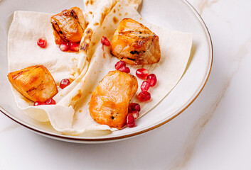 Grilled chicken with pomegranate on a warm flatbread served on a plate