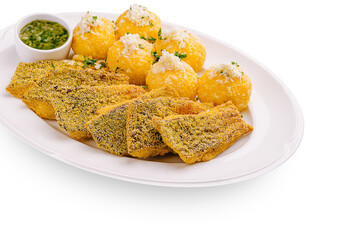Delicious fried fish served with cassava balls and green sauce on a white plate