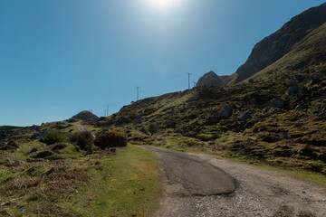 Winding gravel road through hilly terrain with utility poles and natural landscape