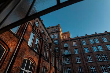 Upward view of historic red brick buildings forming courtyard with multiple levels and traditional European architecture