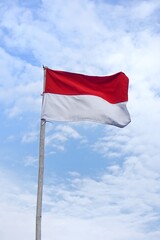 Indonesian flag waving against blue cloudy sky