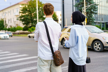 Young adults waiting to cross the street in the city during early evening hours while dressed for...