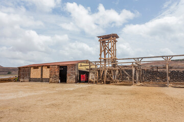 Colorful daytime photograph of traditional salt flats on Sal Island, Cape Verde. Outdoor landscape showcasing vibrant salt pans and distant silhouettes of unidentified people in the background. Captur