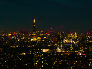 Fototapeta premium Bright city lights reflect off the Thames as iconic landmarks stand out against the night sky in London, creating a stunning atmosphere.