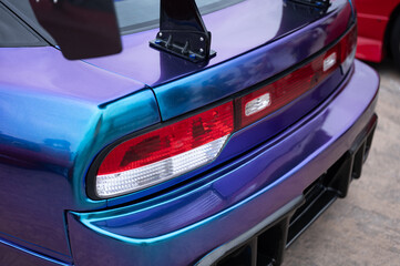 Close-up of the rear taillights and wing mounts on with an iridescent blue and purple vinyl wrap, showcasing its custom JDM tuning
