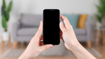 Smartphone in Hand: A modern smartphone, its screen blank, is held gently in a person's hands against the backdrop of a comfortably furnished living space. Suggesting everyday use and communication