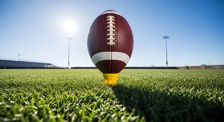 American Football on Tee Under Bright Sun on Green Field