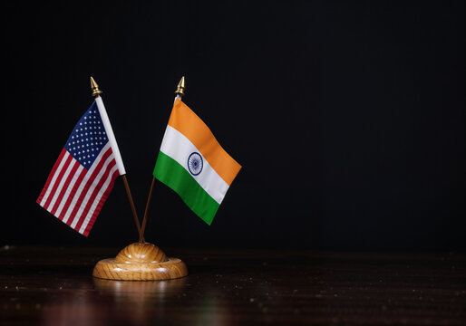 USA and India flags signify international relations on a wooden surface against dark backdrop