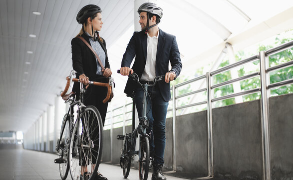 Commuting to work with bicycle. Businessman businesswoman cycling to office in downtown district. Modern diverse people use eco transportation on city street. Environmental pollution, climate change.