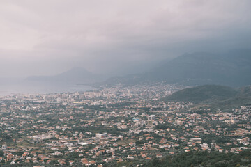 Panoramic View of Coastal City with Mountains and Cloudy Sky