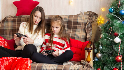 Happy family mother and daughter laugh and play video games together using a video game console on...