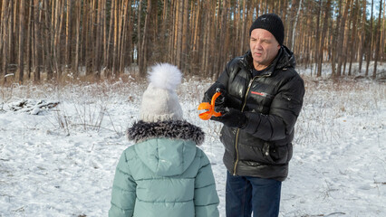 Little girls with her grandfather walk in a snowy forest, have fun together