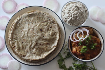 Bajra roti stack with onion, bajra flour and chicken curry traditional, comforting Indian meal