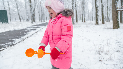 Child walking in the snow park enjoys the first snow in winter
