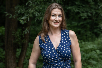Naklejka premium Portrait of a beautiful middle-aged woman in a summer park