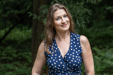 Fototapeta premium Portrait of a beautiful middle-aged woman in a summer park