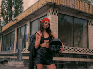 Confident woman in red bandana and crop top with motorcycle helmet.