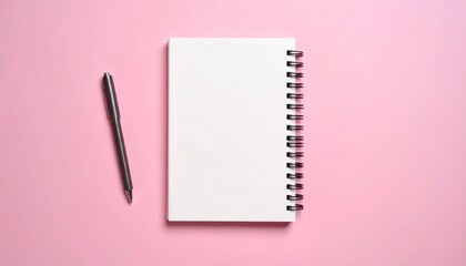 A spiral notebook with pen isolated on a plain pink background
