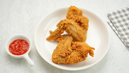 Crispy fried chicken wings on white plate/Crispy fried chicken wings served with chilli sauce on white plate
