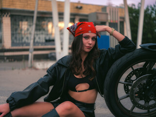 Stylish Woman Biker Sitting Ground with Motorcycle at Gas Station