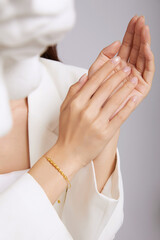 Close-up of a young woman elegantly showcasing a gold bracelet on her wrist.