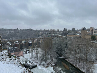 Panoramic view of the Grund district covered in snow during winter, highlighting the train bridge...