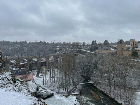 Panoramic view of the Grund district covered in snow during winter, highlighting the train bridge over the Alzette River. Luxembourg