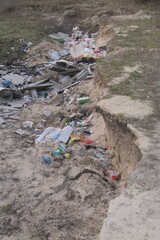 Illegal landfill with household garbage, plastic bottles, construction debris and waste dumped in...