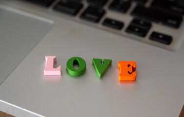 Colorful Wooden Letters Spelling Love on Laptop Keyboard Surface