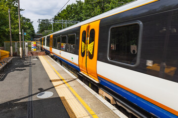 London Overground train at suburban station platform, orange livery, London, UK © SellStock