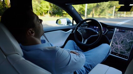 Male businessperson experience to ride an autonomous self driving electric car at urban road....