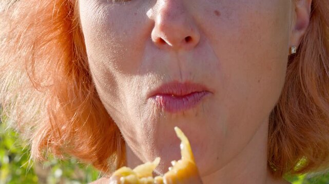 Woman eating a fresh fig. A close-up of a person's mouth eating ripe figs, a vitamin fruit, symbolizes the consumption of healthy and environmentally friendly food.
